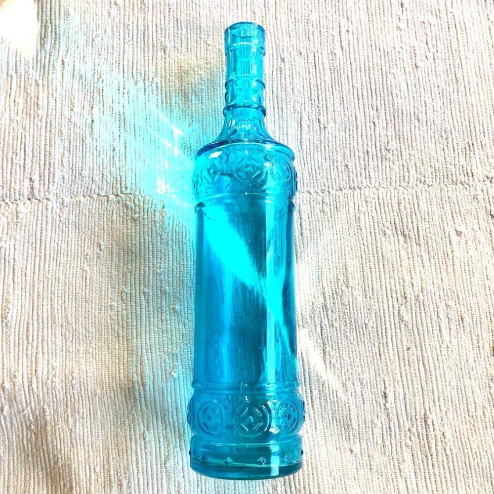Turquoise Glass Bottle with ornate relief flower pattern.